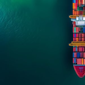 Aerial view of a cargo ship loaded with colorful containers at a commercial dock, representing global trade and logistics